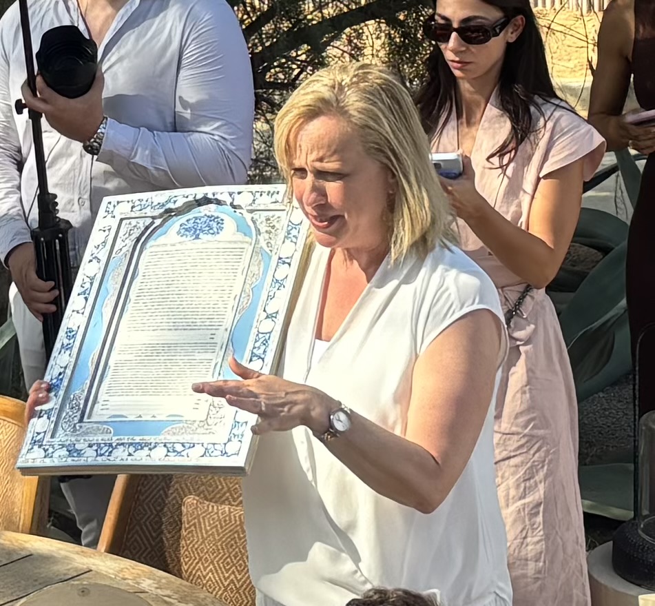 Rabbi Abby Sosland holding up a ketubah at an outdoor wedding